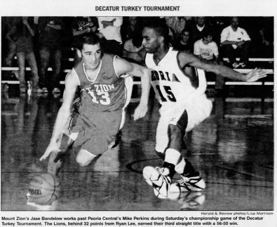 Mt. Zion's Jase Bandelow works past Peoria Central's Mike Perkins